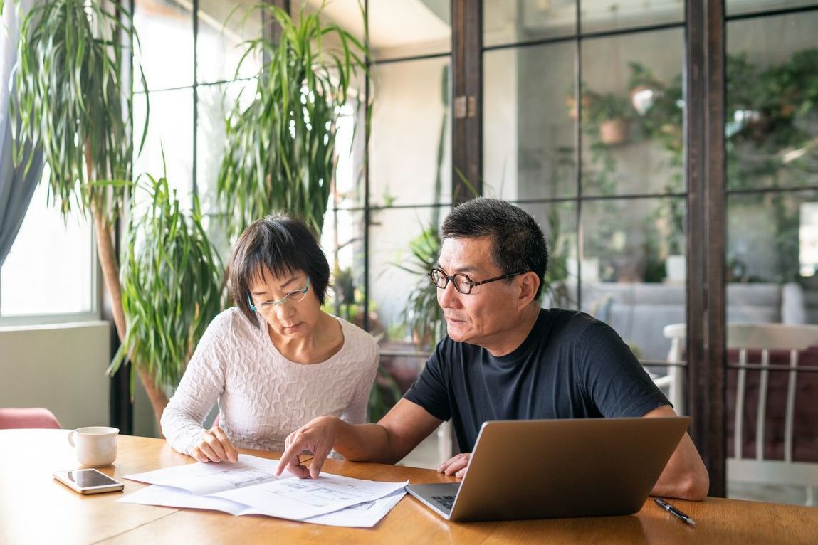 Mature couple looking over home remodeling plans at table.