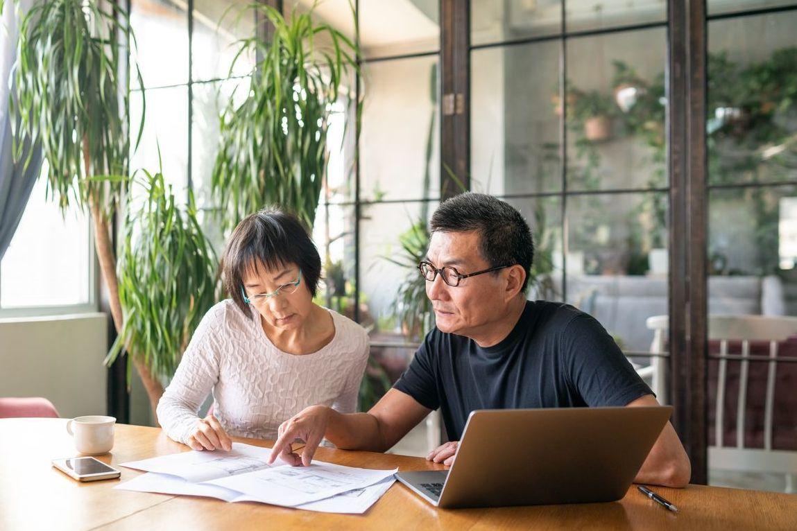 Mature couple looking over home remodeling plans at table.