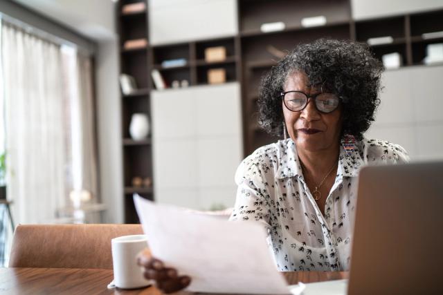 Senior woman using laptop at home to plan and pay bills.