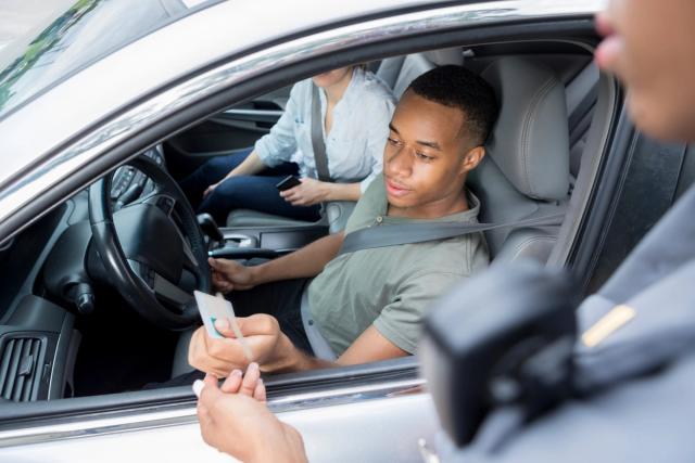 Driver handing identification to a police officer.