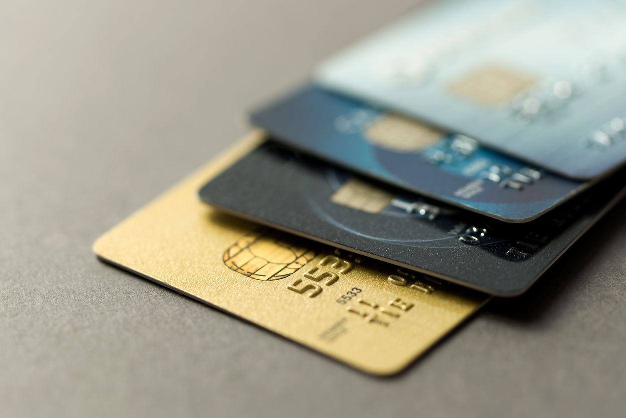Stack of secured and unsecured credit cards on a table.