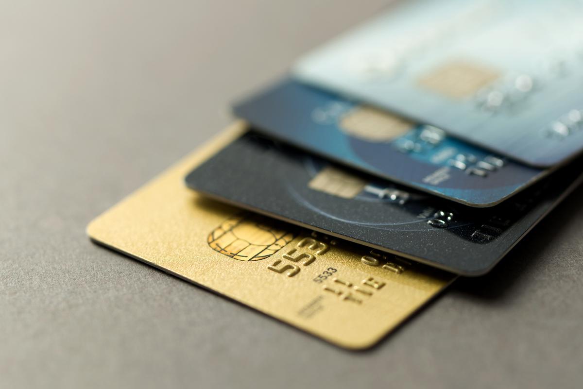 Stack of secured and unsecured credit cards on a table.