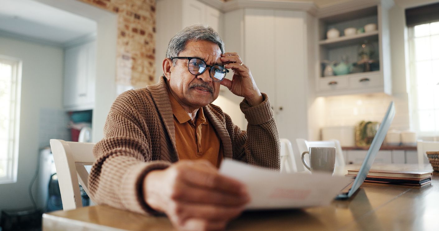 A senior man sitting in front of computer and doing financial review.