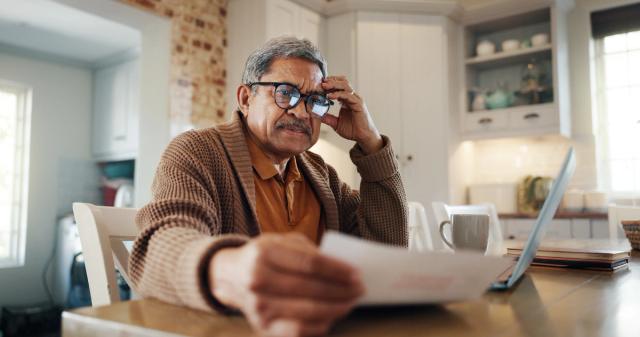 A senior man sitting in front of computer and doing financial review.