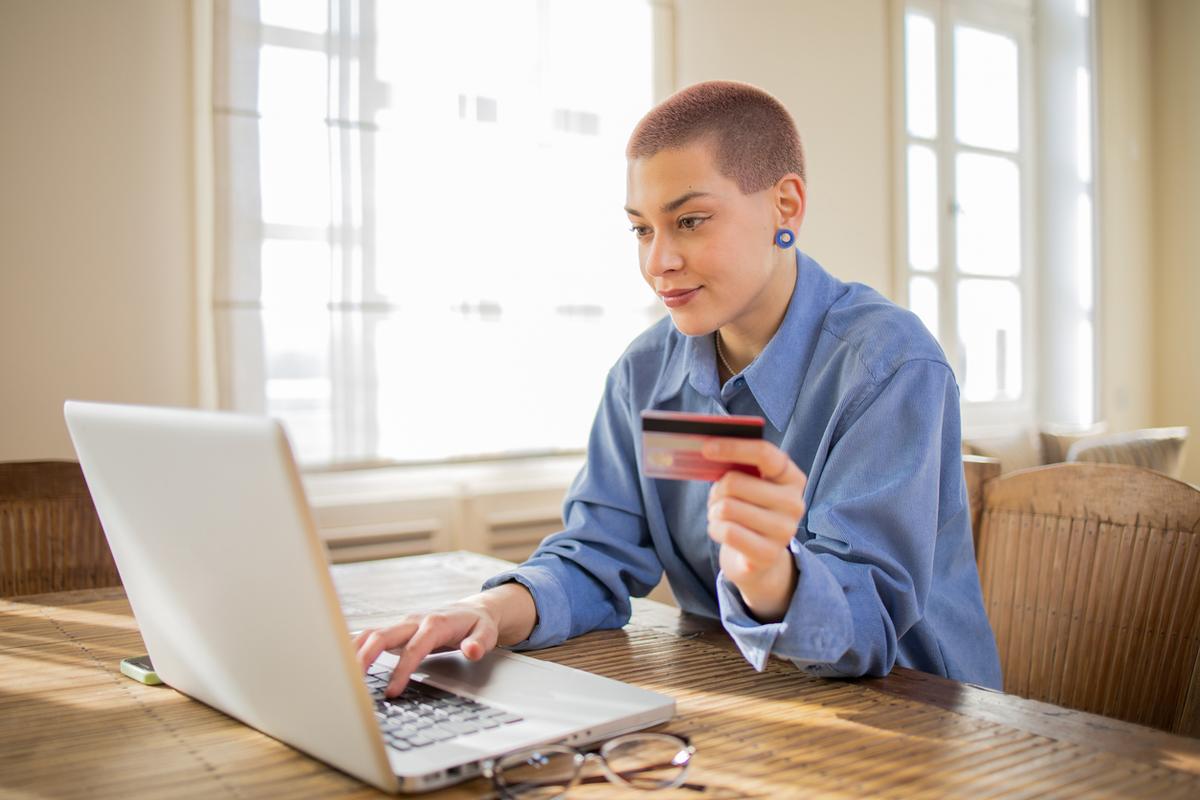 Young person shopping online at home using credit card.