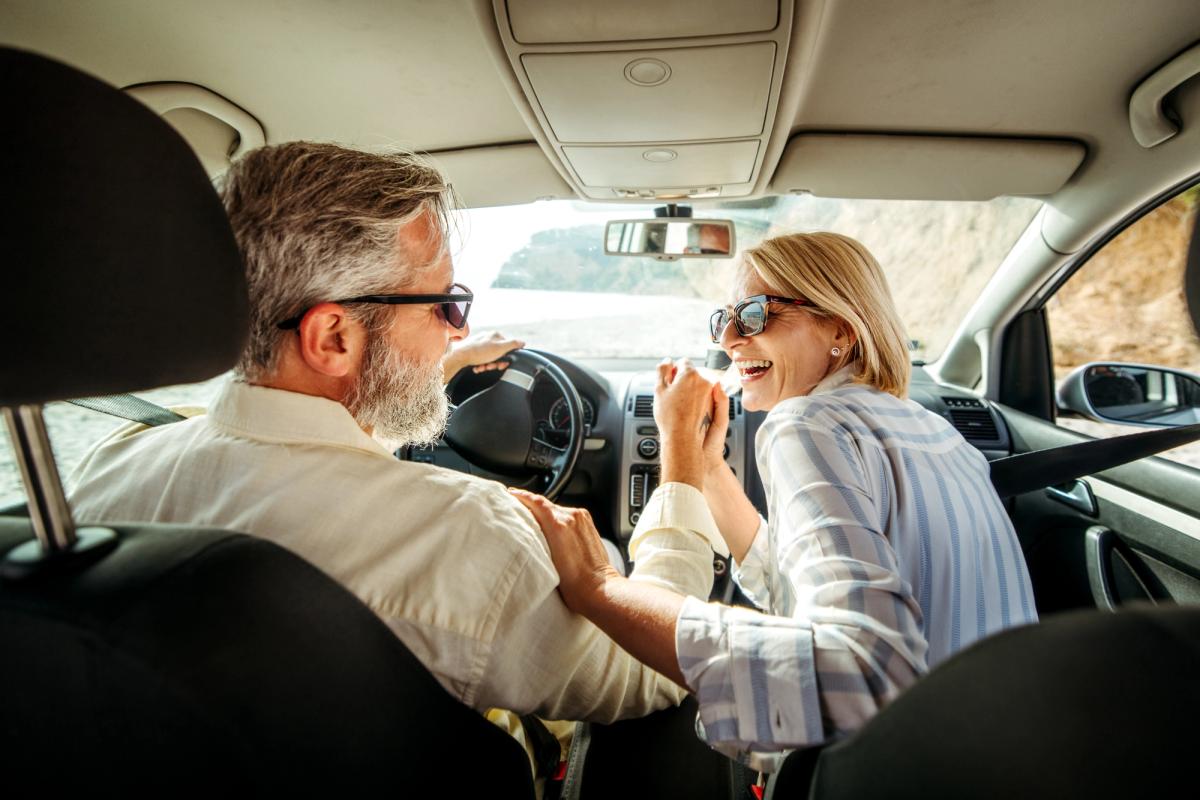 Senior couple laughing while riding in a car together.
