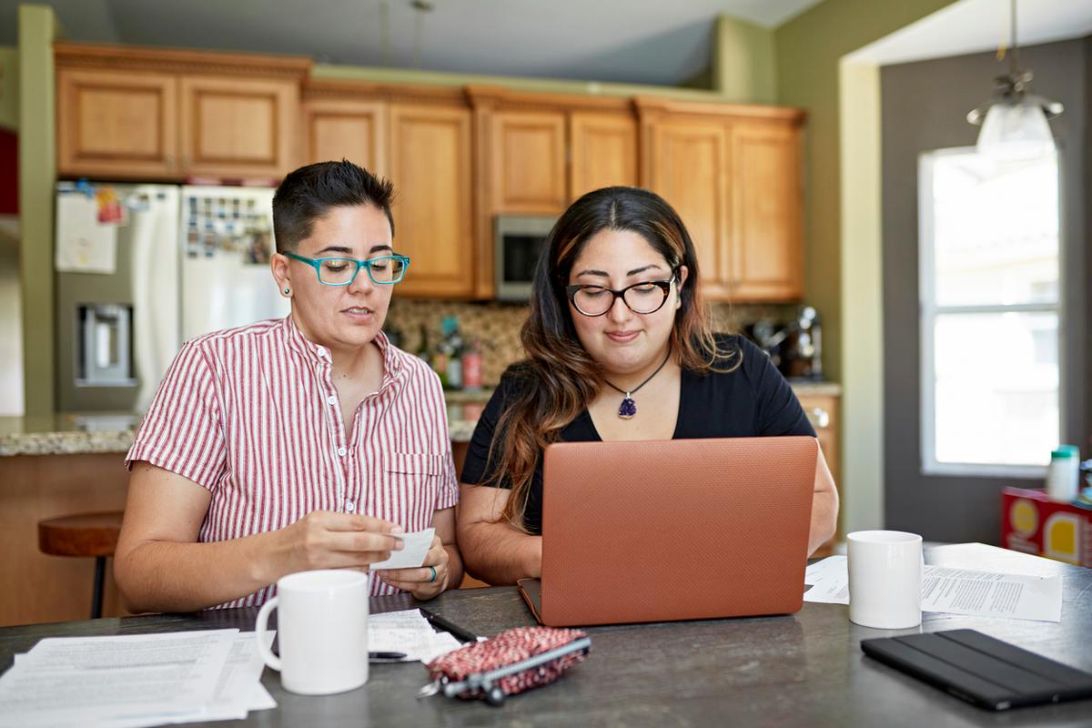 Couple sitting in a kitchen reviewing finances on a laptop at home.