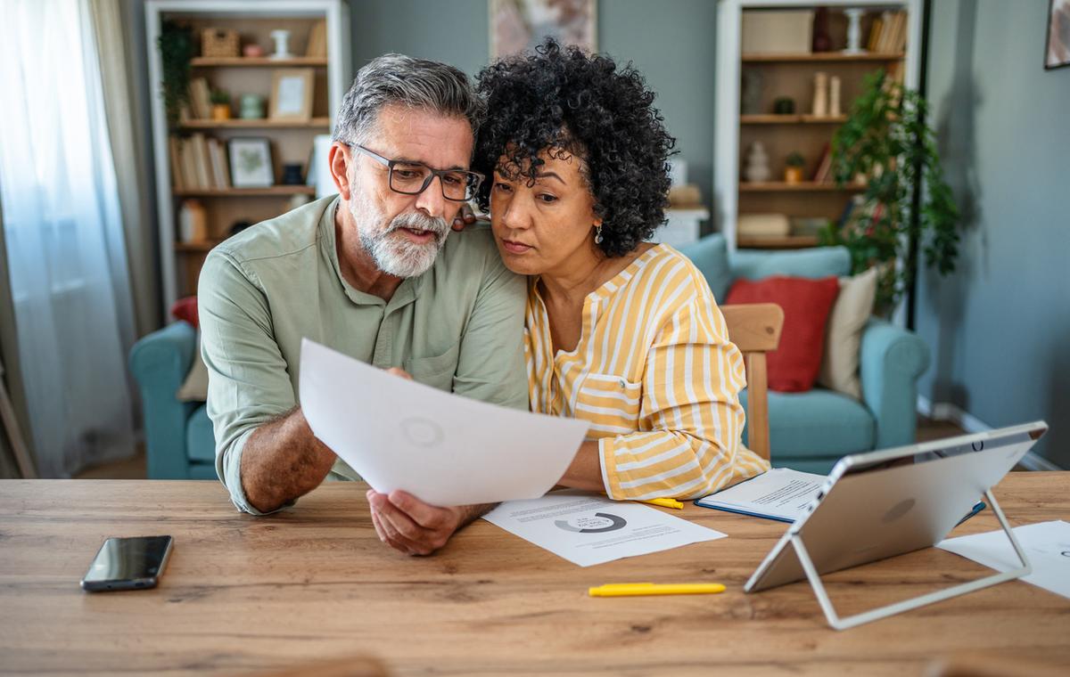 Mature couple manages expenses and bills together at home.