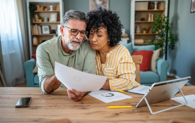 Mature couple manages expenses and bills together at home.