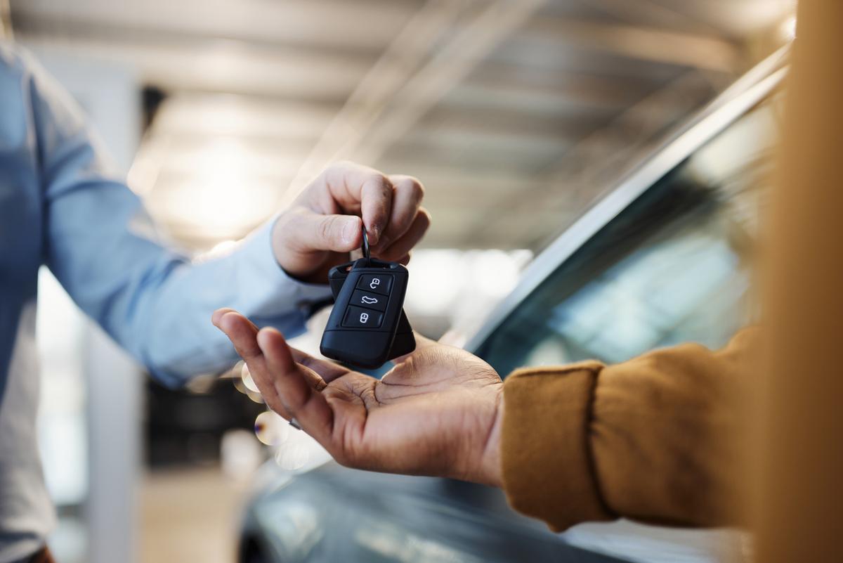 Person receiving car keys beside a vehicle.