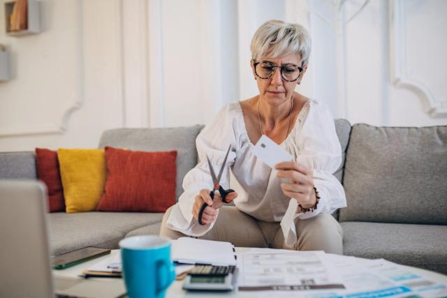 Woman cutting her credit card at home after closing her credit card account.