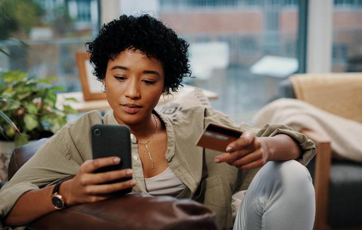 Young woman holding her phone and checking her credit card limit.