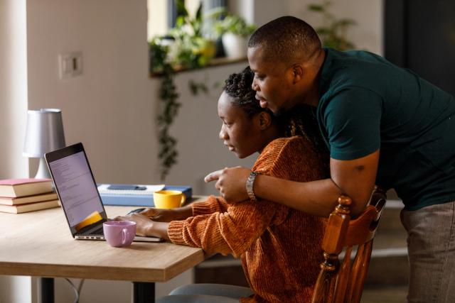 Young couple reviewing finances together on laptop from home.
