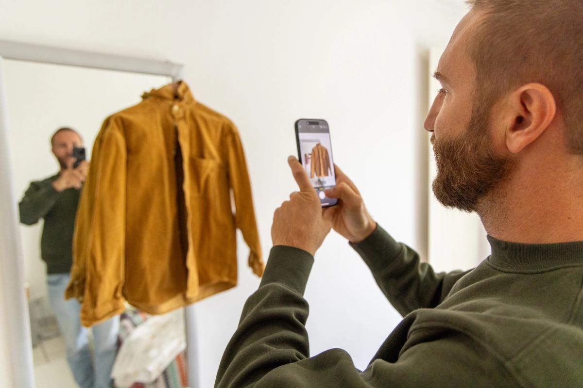 Man photographing vintage shirt for online clothing sale.
